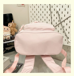 Detail of pink nylon backpack base and padded shoulder straps on a glass table