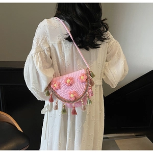 Detail of pink crochet bucket bag with 3D floral accents and bohemian fringe trim