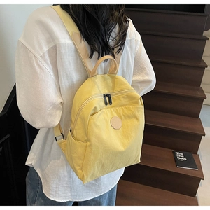 Close-up of yellow nylon backpack with premium leather handles on a wooden staircase