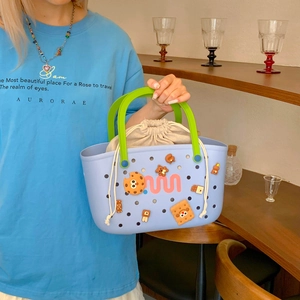 Detail of light blue EVA tote bag with green handles and cute cartoon charms accessories