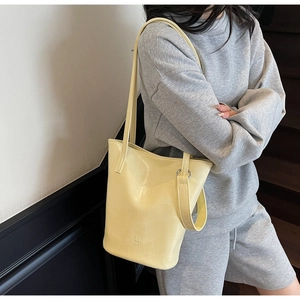 Detailed view of pale yellow bucket bag with crocodile texture and MER PAI embossed logo