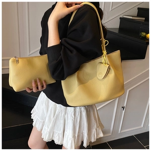 Macro view of light yellow tote bag with matching zippered pouch and pebbled leather texture
