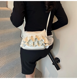 Detail of a creamy white ruffled crossbody bag with glossy leather texture on a model
