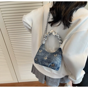 Detail of blue denim shoulder bag with silver butterflies and rhinestones on a female model