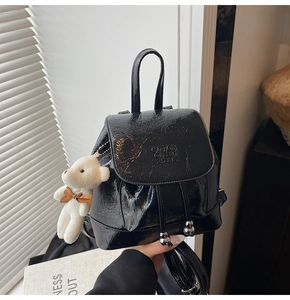 Detail of black glossy bucket backpack featuring drawstring with silver metal spheres
