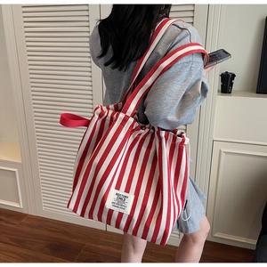 Detail of red and white striped canvas tote bag with drawstring and brand label