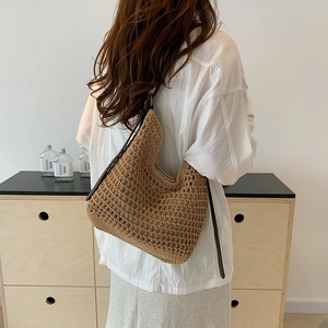 Detailed back view of a beige hobo woven shoulder bag with dark brown strap and hollow pattern