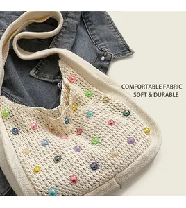 Detailed close-up of cream crochet shoulder bag with colorful beads on denim jacket