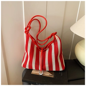 Close-up of red and white striped mesh bag with elegant red knotted faux leather strap