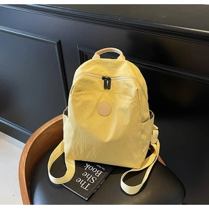 Macro shot of lightweight light yellow nylon backpack on chair with front zipper pocket