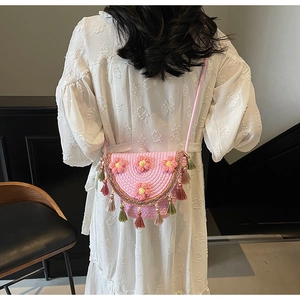 Detail of pink woven bucket bag with 3D floral accents and colorful tassel fringe