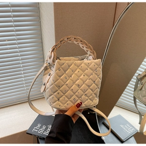 Close-up of beige quilted bucket bag with rhinestone details and woven handle