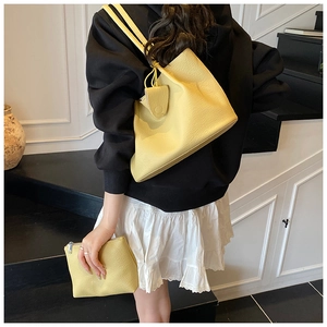 Close-up of a pale yellow lychee pattern leather tote bag set on a shoulder