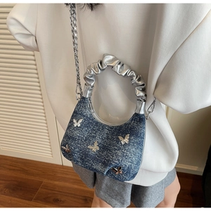 Blue denim crossbody bag with silver butterfly charms and metallic scrunchie handle