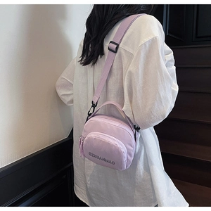 Detail of light purple nylon crossbody bag with adjustable wide strap on model