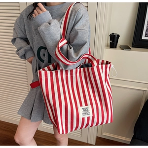 Detail of red and white vertical striped canvas tote bag with woven logo label