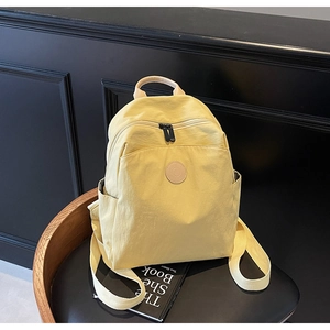 Detail view of lightweight yellow backpack featuring smooth zippers and a leather logo patch