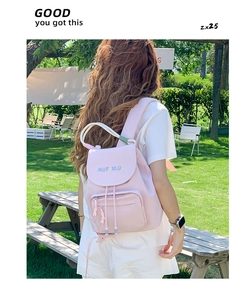 Pink waterproof nylon backpack detail with rainbow lettering on a park bench outdoors
