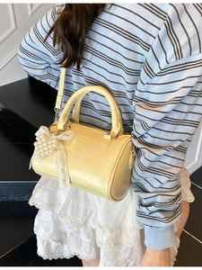 Sac cylindrique jaune texturé avec breloque perle et ruban dentelle sur modèle