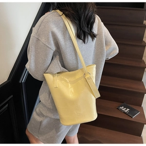 Detailed close-up of yellow stone-pattern tote bag featuring silver metal rings and logo