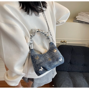 Dettaglio borsa in denim con farfalle argentate in rilievo e manico metallico plissettato