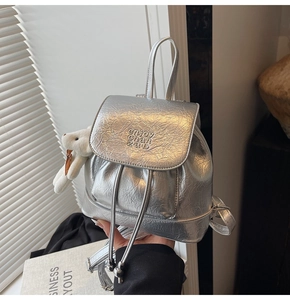 Detail showing metallic silver textured leather backpack with plush bunny charm accessory