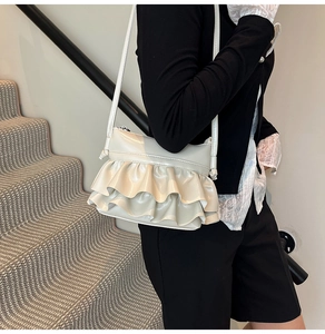 Detail of creamy white pleated ruffle shoulder bag with shiny PU leather finish