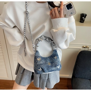 Detail of blue denim crossbody bag with silver butterfly charms and metallic strap