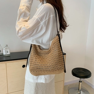 Detail of hand-woven straw shoulder bag with wide mesh pattern and leather straps
