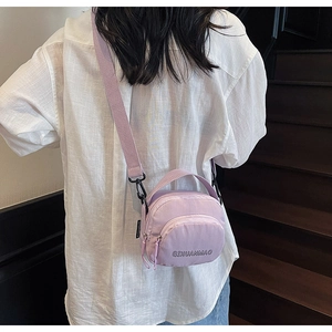 Detail of light purple nylon crossbody bag with adjustable strap worn by a model