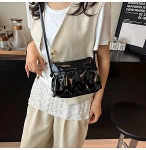 Detail of black glossy leather bucket bag with layered ruffle design on model