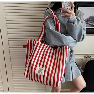 Detail of red and white striped canvas tote bag showing drawstring closure and brand label