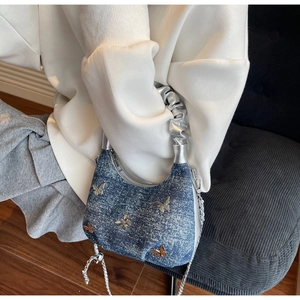 Detail of blue denim hobo bag featuring silver metal butterfly charms and rhinestones
