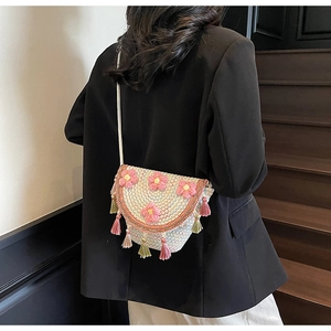 Detail of white woven bucket bag with 3D pink flowers and colorful tassel accents