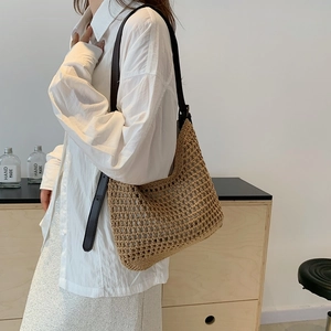 Detail of woven straw tote bag with brown leather strap and openwork mesh pattern