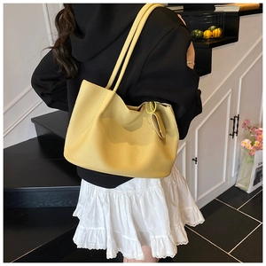 Detailed texture of yellow litchi pattern tote bag with pendant carried by a model
