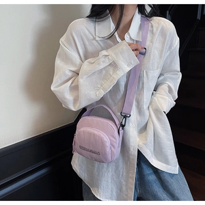 Detail of light purple canvas crossbody bag with top handle and adjustable strap