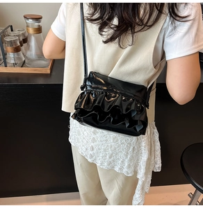 Detail view of a black ruffled leather crossbody bag styled with a modern outfit
