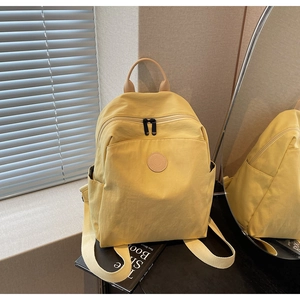Detailed close-up of a vibrant yellow travel backpack with leather logo and cream straps