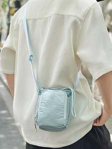 Light blue nylon crossbody water bottle bag with adjustable strap and front zipper pocket
