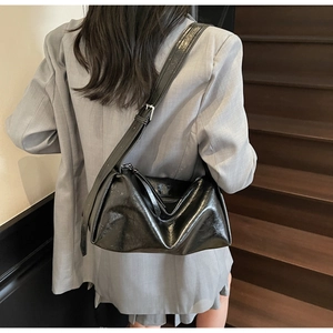 Rückansicht einer glänzend schwarzen Boston-Tasche zu grauem Anzug mit Silberbeschlägen