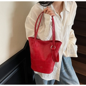 Close-up of bright red crocodile embossed bucket bag with silver metal ring details