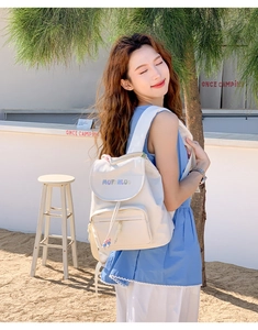 Detail of cream canvas backpack featuring colorful embroidery and drawstring closure