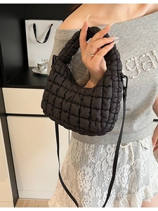 Black quilted cloud handbag with adjustable strap shown on a model in a modern home