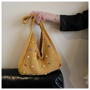 Detail of yellow knitted tote bag featuring multi-colored pearl accents and thick handles