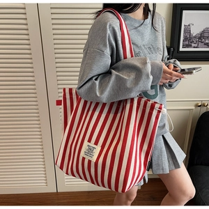 Detail of red and white striped canvas tote bag showing retro label and drawstring