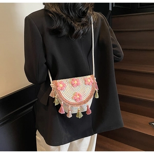 Detail view of woven mini bucket bag with 3D pink flowers and colorful tassel trim