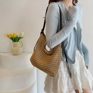 Detail of woven straw tote bag with brown shoulder straps and hollow mesh design