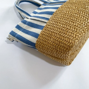 Close-up of blue striped canvas and straw woven texture on a casual beach tote bag