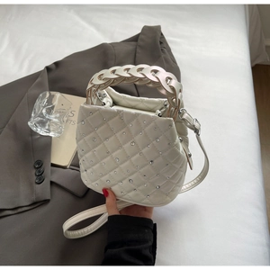 Dettaglio della borsa a secchiello bianca trapuntata con strass e manico intrecciato